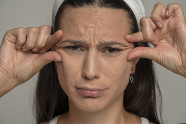 一个悲伤的年轻女人的肖像紧掐着她眼睛旁的皱纹图片下载