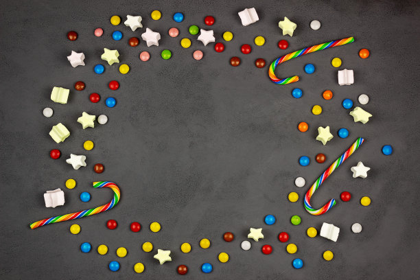 在黑色背景上的多色糖果在一个框架的形式。棒棒糖,焦糖,棉花糖。图片下载