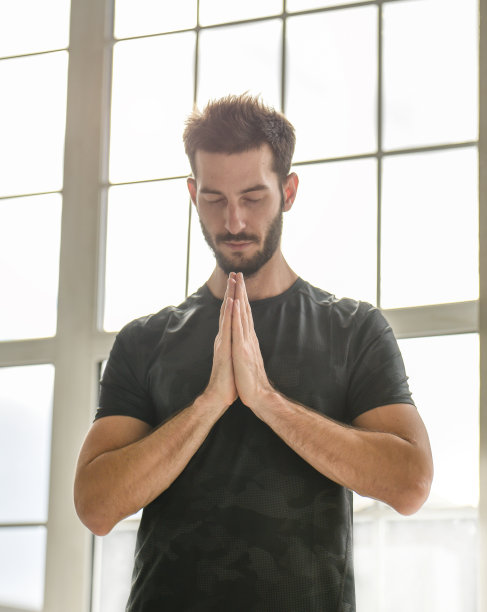 窗户后面有个年轻人。瑜伽教练。一个男人偷窥。图片下载