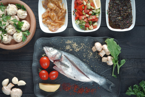 新鲜的鲈鱼配香草和柠檬放在木制砧板上图片下载