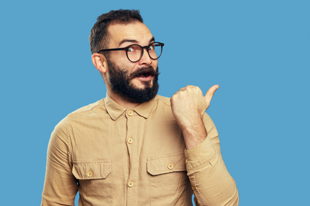 惊讶的男学生指着被隔离在蓝色墙上的空地图片下载