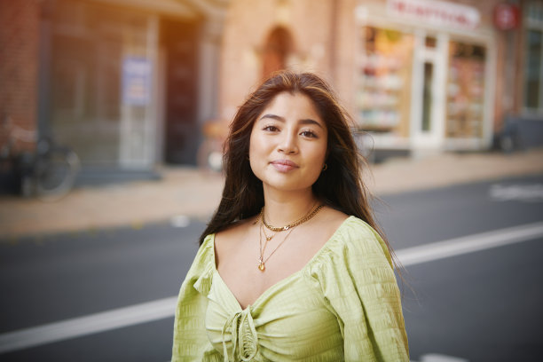 年轻的亚洲女子穿着绿色的衣服走在街上图片下载