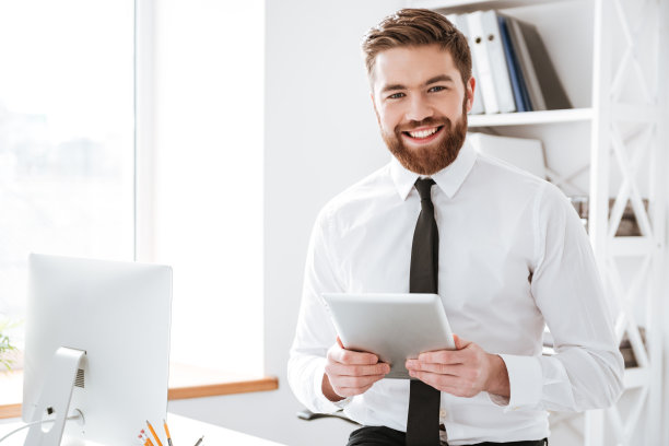 兴高采烈的年轻商人手里拿着平板电脑。图片下载