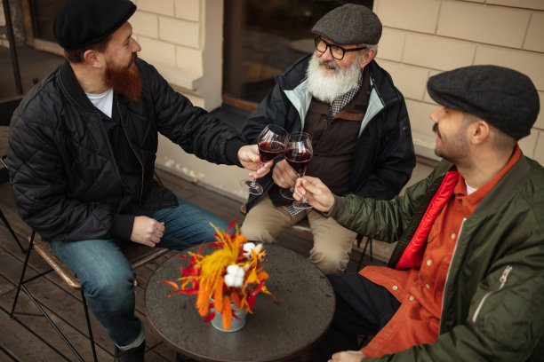 温暖的秋日，一群男人，一群朋友在咖啡馆聚会。喝着红酒，碰杯图片下载