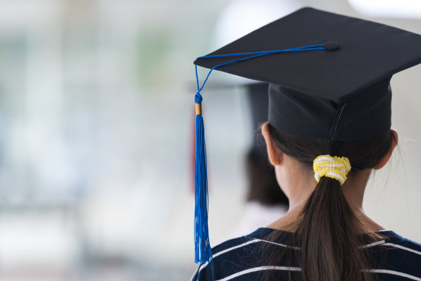后视图亚洲女学生毕业带着毕业帽手持卷证书。毕业典礼概念照片图片下载