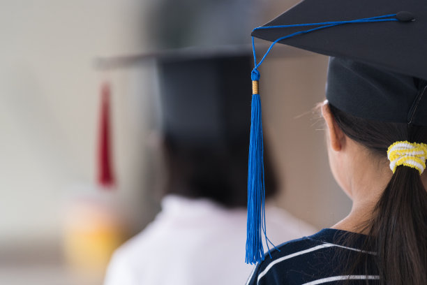 后视图亚洲女学生毕业带着毕业帽手持卷证书。毕业典礼概念照片图片下载