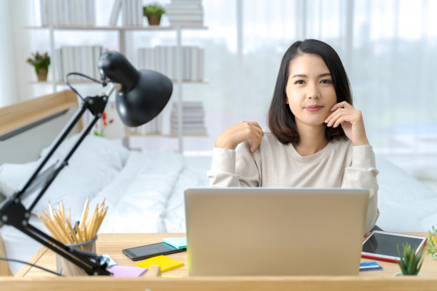 一张明亮的亚洲女人在卧室里工作的照片。这个想法是:工作形式家庭，财务，营销，光明，肖像，简单。图片下载