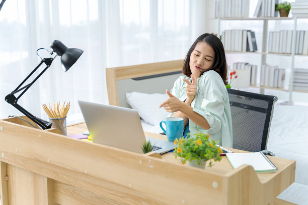 一张明亮的亚洲女人在卧室里工作的照片。这个想法是:工作形式家庭，财务，营销，光明，肖像，简单。图片下载