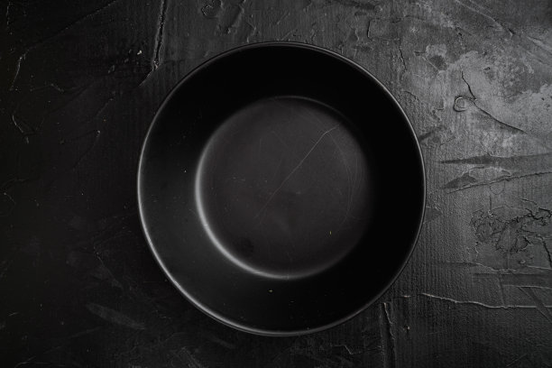 黑色碗，带有文本或食物的复制空间，带有文本或食物的复制空间，俯视图平铺，在黑色的深色石头背景上图片下载