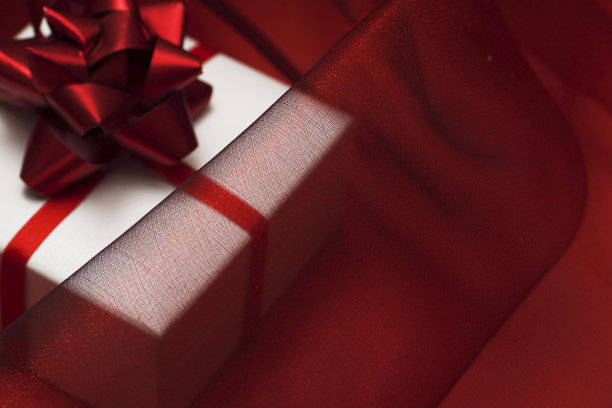 礼品盒下透明的红色真丝织物。圣诞节，新年，生日，情人节，妇女节，购物销售理念。图片下载