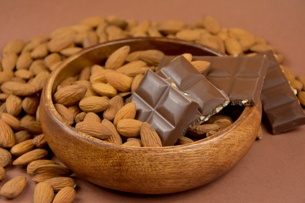 牛奶巧克力棒与杏仁在木碗库存图像图片下载