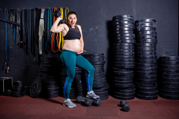 肌肉发达的运动孕妇在体育器材附近姿势。专业运动员怀孕女性。怀孕期间的健康和身体活动。积极运动的怀孕观念图片下载