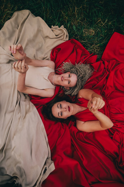 两个穿着长裙躺在草地上的漂亮女人的时尚照片图片下载