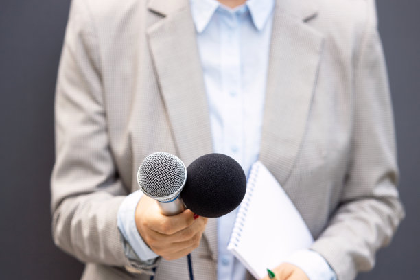 新闻记者或电视记者在媒体活动现场，手持麦克风，进行新闻采访。广播新闻的概念。图片下载