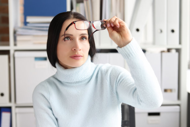 一名女子在工作场所坐着看眼镜图片下载