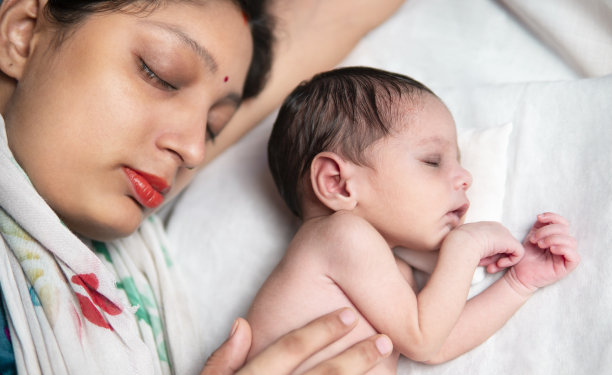 俯视图的图像，母亲和新生儿一起平静地睡在床上。图片下载