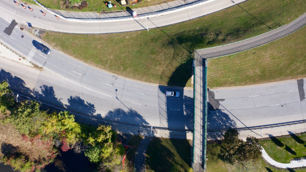 在一个阳光明媚的日子里，在纽约罗克维尔中心，从上往下拍摄的照片直接越过了一个横跨多车道高速公路的人行天桥。图片下载