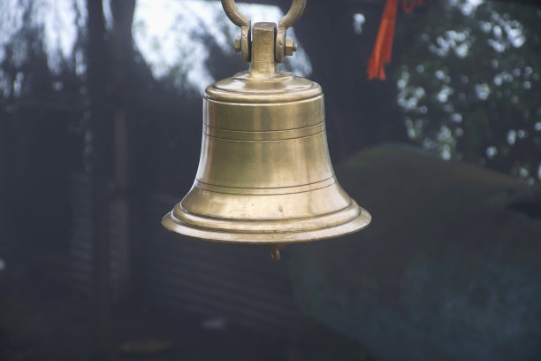 在模糊雾蒙蒙的背景下，两个古老的铜或青铜钟挂在印度寺庙的铁框架上。这张照片拍摄于印度马哈拉施特拉邦Kolhapur的sateri山站。图片下载