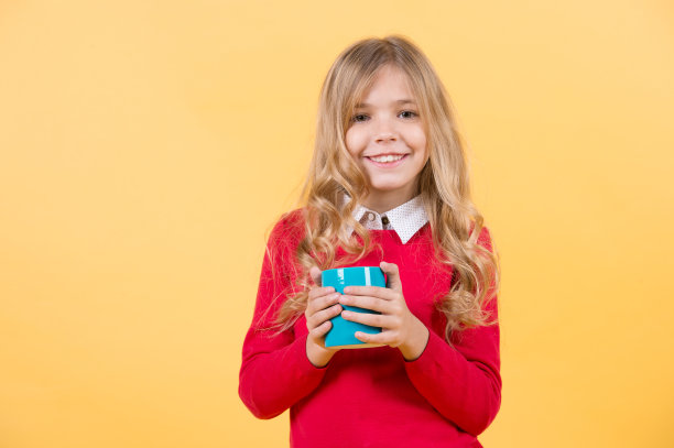 穿红毛衣的金发女孩拿着杯子图片下载