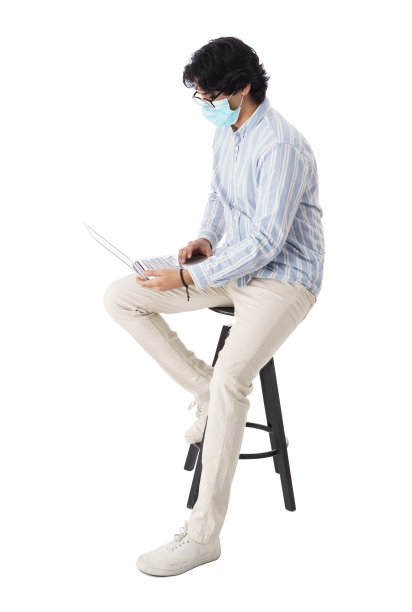 男同学戴着口罩使用笔记本电脑的侧面图图片下载