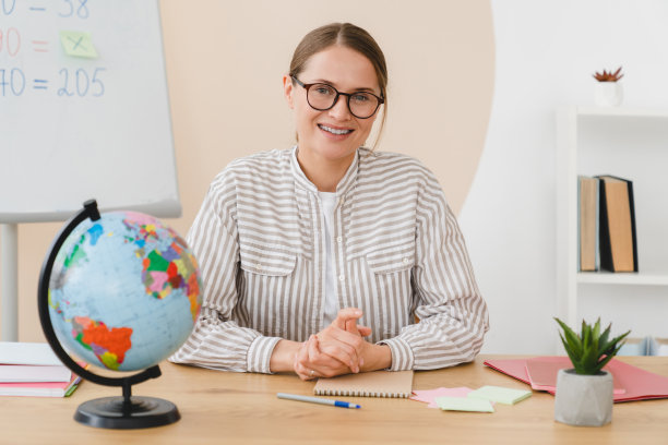 年轻的女数学地理老师，校长，家庭教师，学生讲师在课桌前看着摄像机在学校教室里工作。图片下载