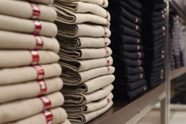 近距离堆放折叠的棕色和黑色裤子在架子上图片下载