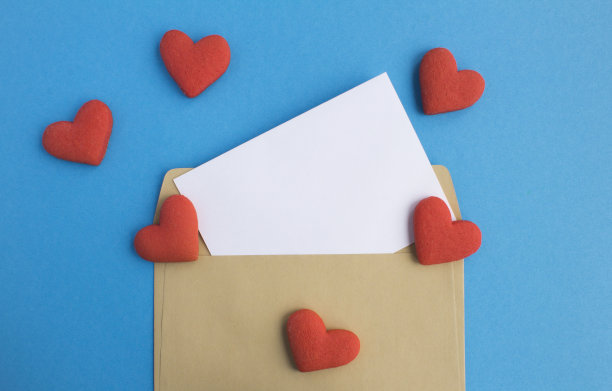 蓝色背景上有空白的白纸、信封和红色的心形饼干。副本的空间。前视图。图片下载