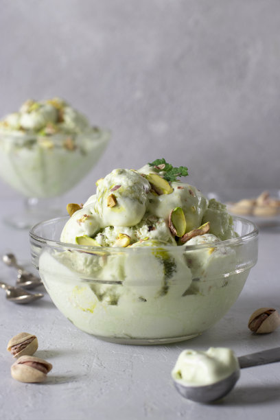 开心果冰淇淋与坚果在透明玻璃冰淇淋碗浅灰色的背景。图片下载
