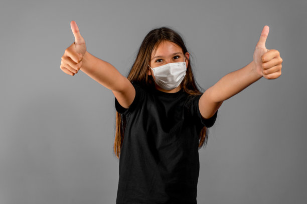 漂亮的照片深褐色长发女孩大拇指向上戴面部流感口罩黑色t恤孤立在灰色背景图片下载