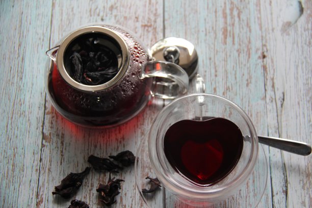 木槿红热茶在一个玻璃杯和一个清晰的玻璃茶壶在木桌。从以上观点。图片下载