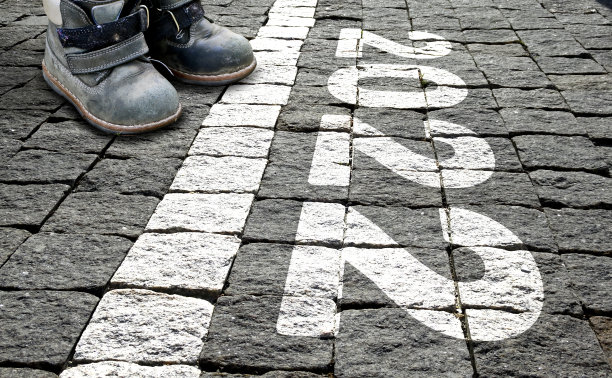 一个穿着童鞋的孩子站在起跑线前的铺路石上，上面写着“2022”。新年的概念，生命的开始，进入成年。图片下载