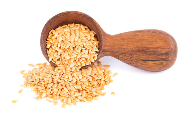 金黄色的亚麻籽放在木勺里，分离在白色背景上。一堆干亚麻籽或亚麻籽。图片下载