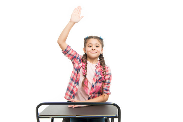 准备回学校了。小女孩在小学背诵课文。可爱的孩子举起手在学校的桌子上孤立的白色。可爱的小女孩很享受她的学校时光图片下载