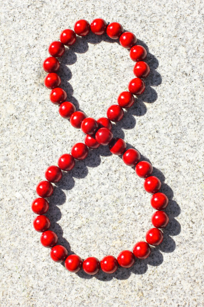 在灰色的背景上，被太阳照亮的红色大木珠图片下载