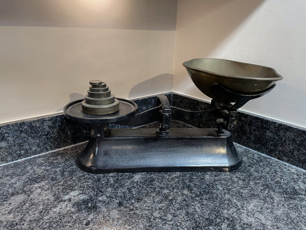 在卤素聚光灯下，在花岗岩的工作台上放着一堆圆盘砝码的复古式称重秤图片下载