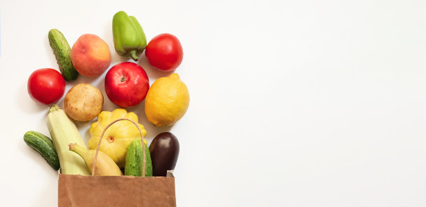 一个纸质购物袋，里面有蔬菜和水果，西红柿，黄瓜，南瓜，胡椒，柠檬，茄子，西葫芦，香蕉，苹果，桃子，白色背景图片下载