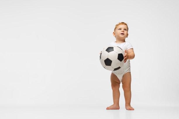 小男孩的全身肖像，孩子在紧身衣踢足球孤立在白色的背景图片下载