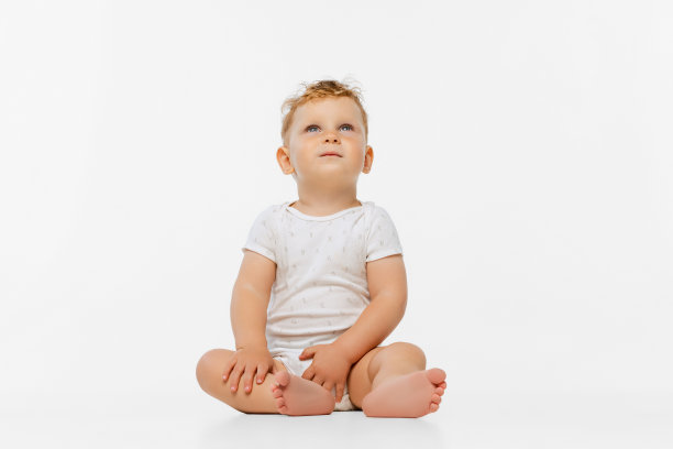 全身小男孩的肖像，孩子穿着紧身衣平静地坐着，抬头看着孤立的白色背景图片下载