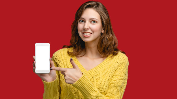 手机复制空间模板。摄影棚里的女人拿着红色背景的智能手机。概念与人空白屏的小玩意。使用广告及应用设备者图片下载
