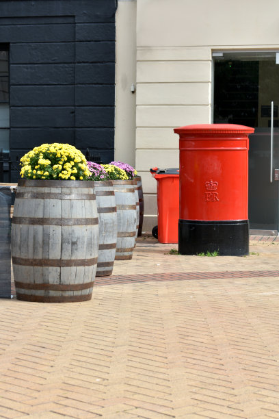 一个红色邮筒的特写，背景是一个红色的回收箱，在夏天的街道上。图片下载