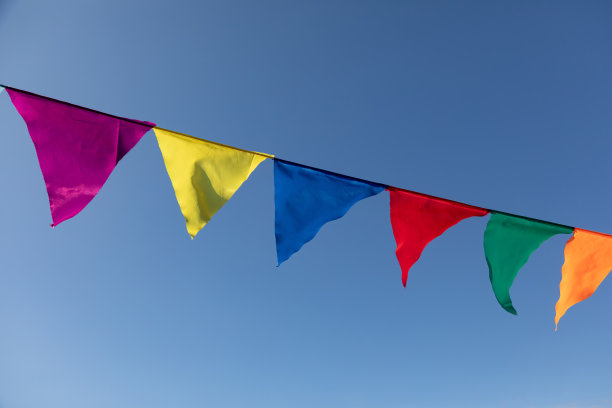 在蓝天的映衬下，鲜艳的三角形旗帜在风中飘扬图片下载