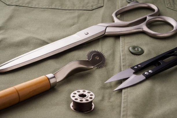剪刀，针，线轴，锉刀摆在一件缝好的衬衫上，这是特写。裁缝或时装设计师的办公桌。缝纫服装、缝纫配件的概念。时尚设计元素图片下载