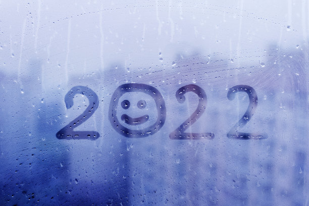 数字2022的新年与笑脸上溅着雨雾玻璃在蓝色窗户图片下载