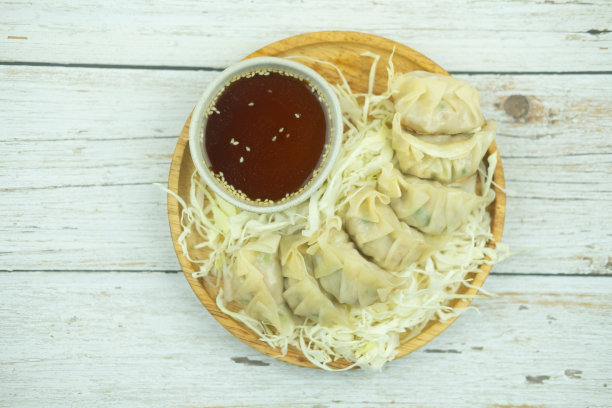 木盘上的蒸饺配上切碎的卷心菜，木桌上放着酱油图片下载