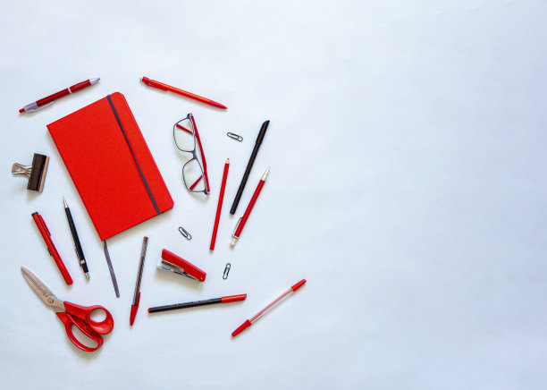 红色笔记本和文具平铺在蓝色背景上图片下载