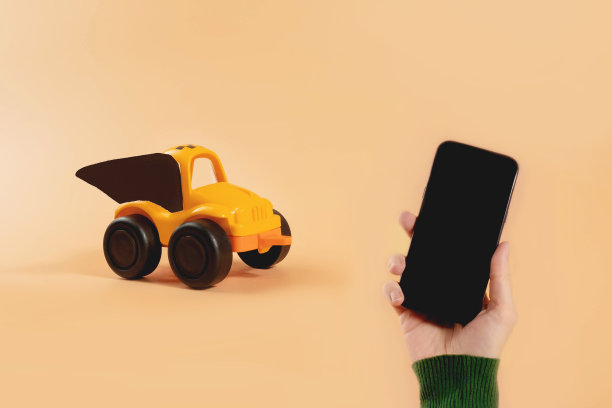 手拿智能手机，黄色玩具出租车与蝙蝠翅膀万圣节服装在米色背景。送花、送孩子、打车。图片下载