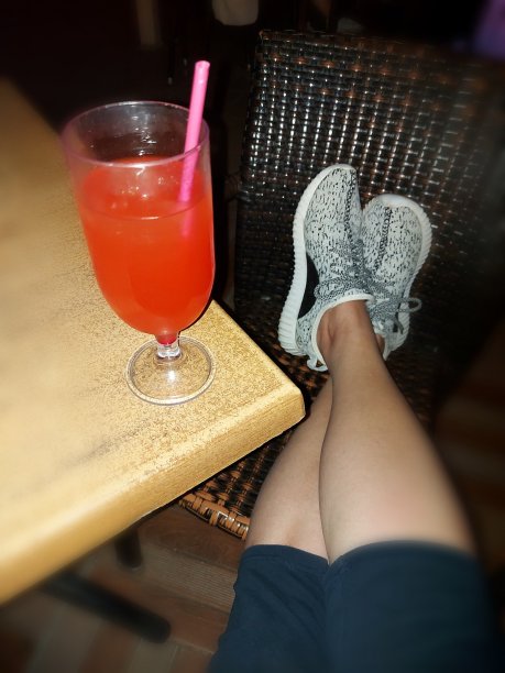 一个女人把脚放在椅子上，桌上放着一杯鸡尾酒图片下载