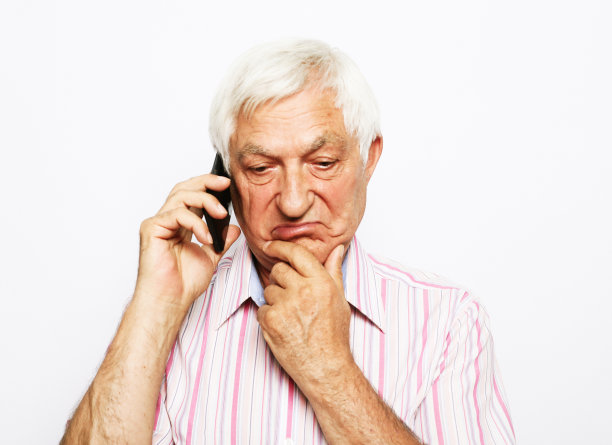 摄影棚里快乐的长者在讲手机，疑惑，艰难的选择，用手摸下巴图片下载