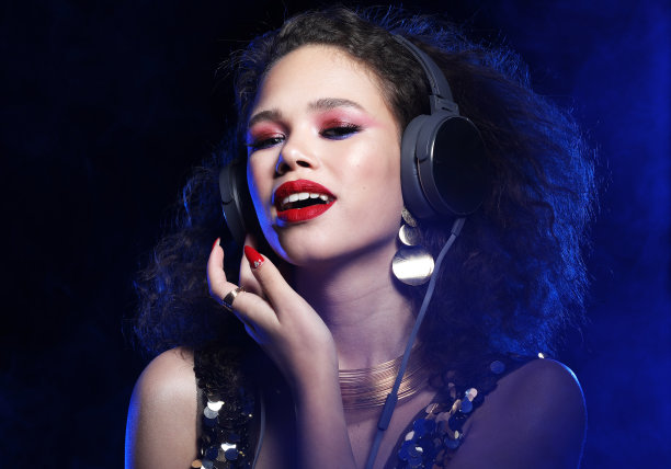 近距离的肖像欢快的年轻非洲妇女与明亮的妆听音乐耳机图片下载