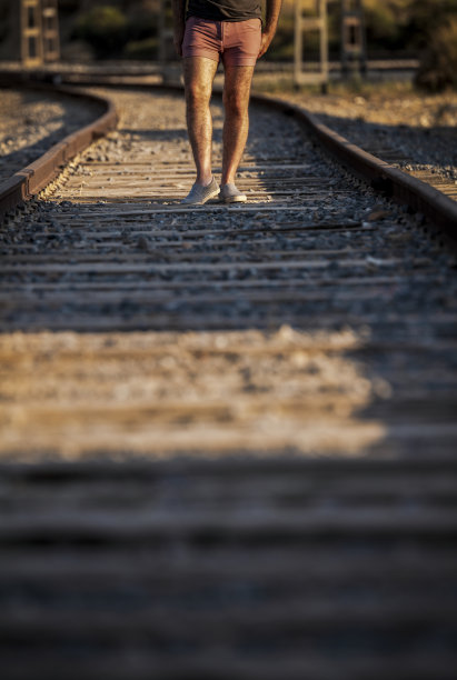 日落时，人腿在铁轨上行走图片下载